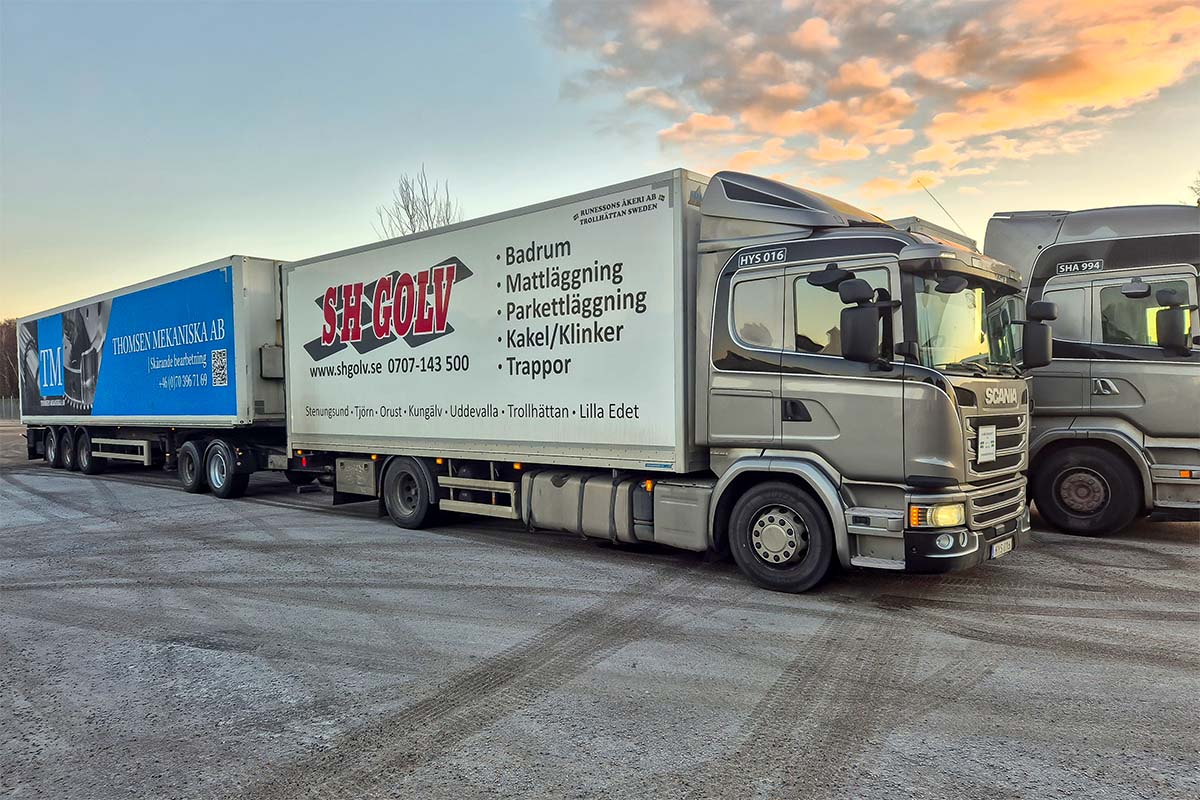 Två lastbilar med släp står bredvid varann i solnedgången